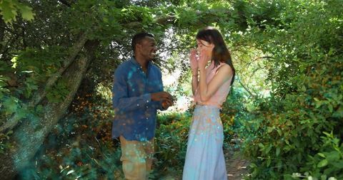 Couple sharing joyful surprise under leafy garden canopy with sunlit pathway