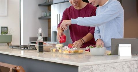 Friends Enthusiastically Preparing Meal in Modern Kitchen