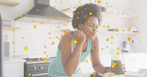 Woman enjoying green smoothie in bright modern kitchen with avocado and wellness vibe