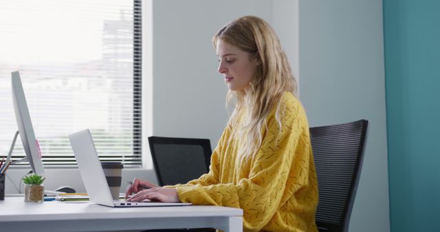 Young woman working on laptop at modern office desk - Download Free Stock Images Pikwizard.com