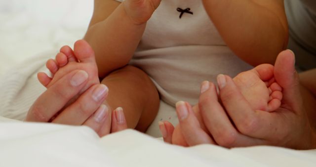 Mother touching her baby daughters tiny toes at home in bedroom