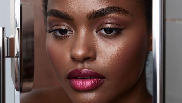 Closeup black woman with dewy skin and fuchsia lipstick framed by polished chrome edges