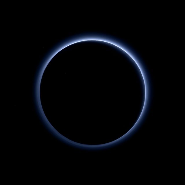 Image depicts blue haze around Pluto captured by NASA's New Horizons spacecraft. Suitable for educational materials about Pluto, discussions about planetary atmospheres, or space exploration visuals.