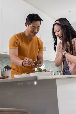 Young couple serving salad at modern kitchen island joyful home cooking moment