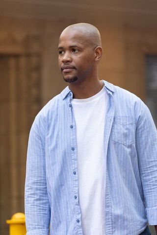 Young man standing on urban street wearing blue striped shirt over white t-shirt casual portrait