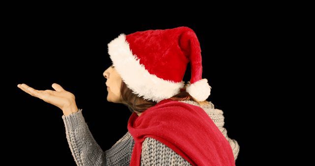 Woman in Santa Hat Blowing a Kiss with Black Background - Download Free Stock Images Pikwizard.com