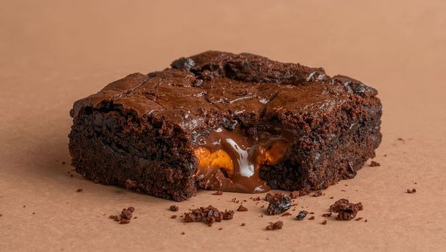 Gooey caramel oozing from fudgy chocolate brownie closeup on kraft paper decadent
