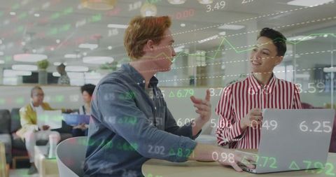 Colleagues Collaborating at Office Workspace with Overlayed Stock Market Data