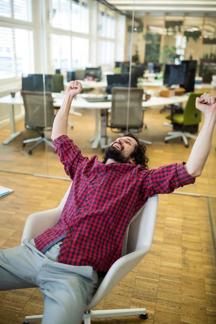 Happy male graphic designer cheering in office