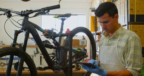 Caucasian Mechanic Using Tablet in Bicycle Repair Shop - Download Free Stock Images Pikwizard.com