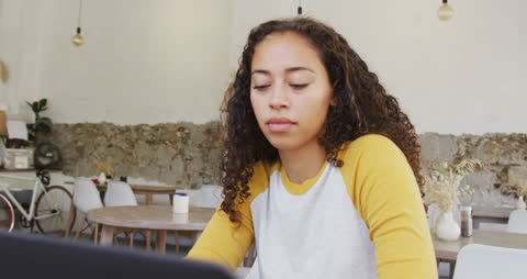 Biracial Woman Working on Laptop in Cozy Cafe Setting