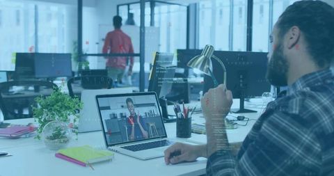 Bearded man engaging in virtual meeting at collaborative open-plan office desk