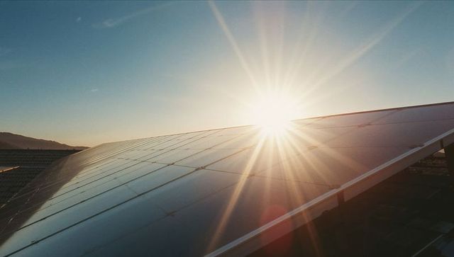 Shimmering Sunrise on Solar Panels at Renewable Energy Farm