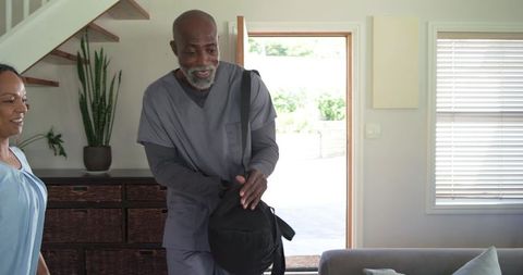 Healthcare worker arriving home after shift with partner in sunlit entryway