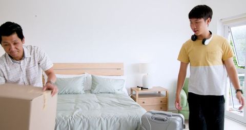 Father and Teenage Son Unpacking in Modern Bedroom