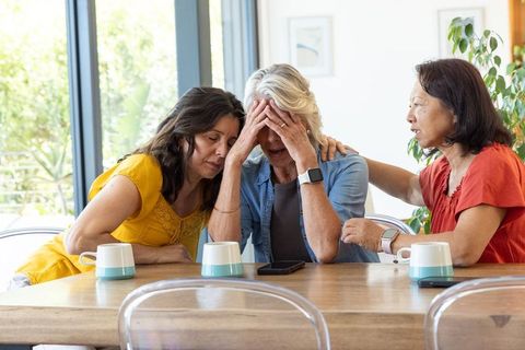 Diverse women comforting senior friend at table, emotional support, empathy and care
