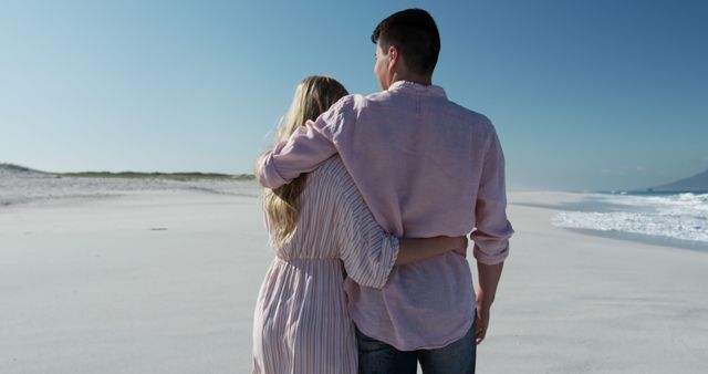 Couple embracing while walking along serene beach looking content and relaxed. Ideal for use in romantic content, travel promotions, relationship advice materials, and depicting serene vacations.