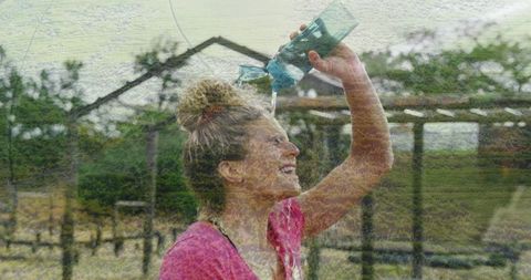 Smiling woman cooling down outdoors with water bottle
