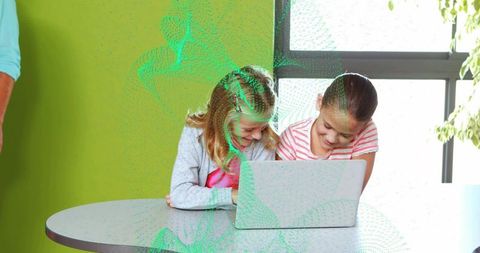 Two girls sharing laptop laughing and learning together in bright modern classroom
