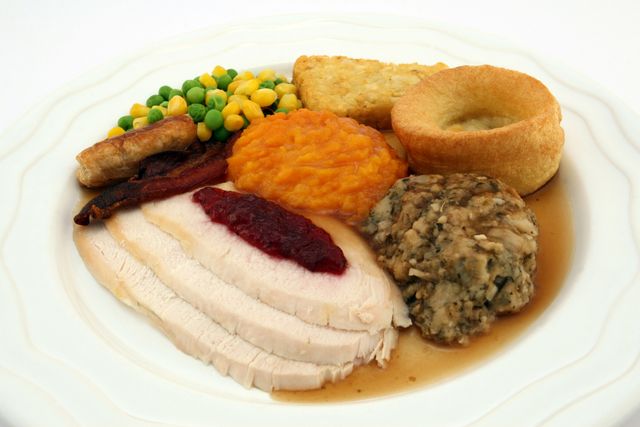 Sliced roasted turkey breast served with stuffing, gravy, hash brown patty, mixed vegetables, and a dollop of cranberry sauce on a white plate. Perfect for use in festive season marketing materials, food blogs discussing holiday meals, or menus for Christmas dinners.
