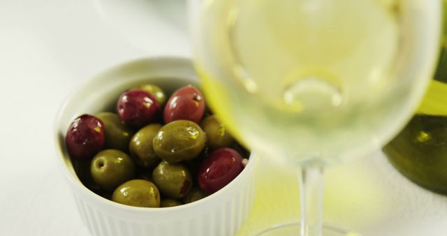 Olives in white bowl next to glass of white wine, close-up - Download Free Stock Images Pikwizard.com