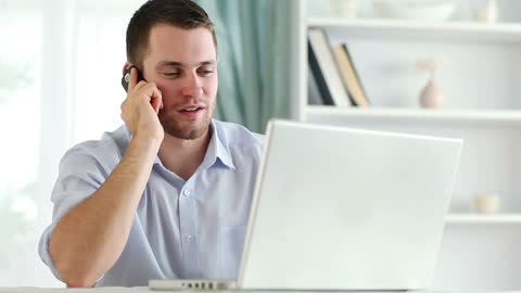 Man Telecommuting from Home Office with Phone Call