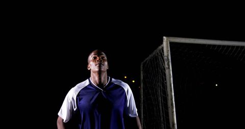 Confident soccer player under night sky at field
