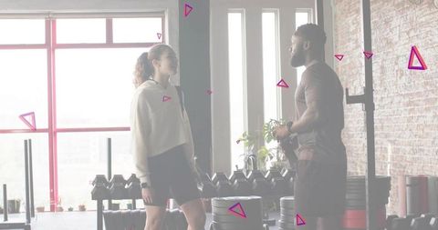 Trainer coaching female client in urban loft gym backlit silhouettes, dumbbells