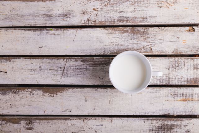 Directly above shot of milk in cup on wooden table, copy space. unaltered, food, drink and healthy eating.