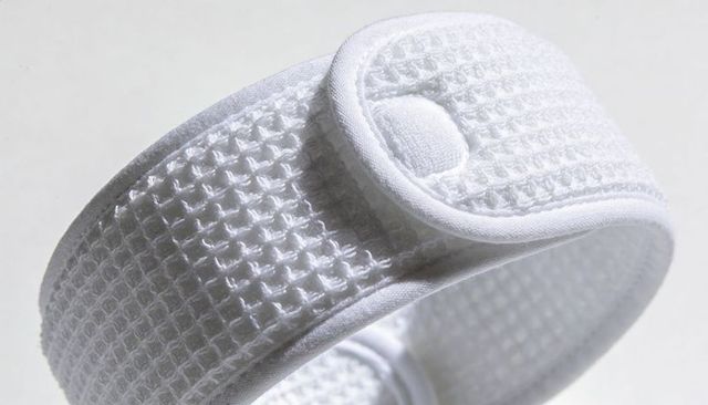 White waffle-weave terry headband with snap closure and piped edges showing texture detail