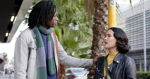 African american man talking with asian woman at bus stop, urban transit conversation