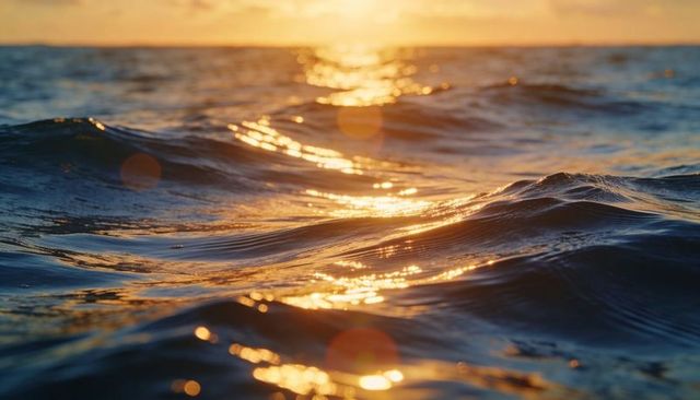 Gliding golden ocean waves reflecting sunset light, shimmering sea surface with lens flare