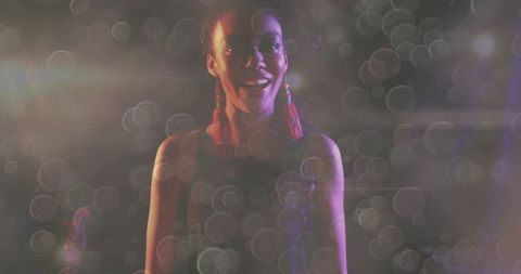 Moody stage performer wearing red tassel earrings bokeh glow live music portrait