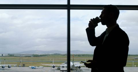 businessman silhouette at airport terminal with coffee and phone - Download Free Stock Images Pikwizard.com