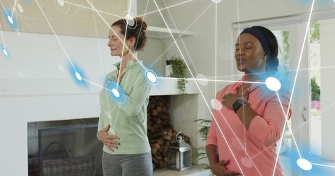 Two women practicing breathwork and mindfulness by fireplace with digital wellness network