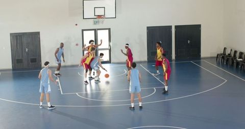 Diverse Male Athletes Battling on Indoor Basketball Court