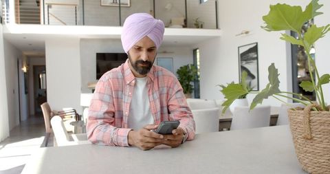 Man in Turban Relaxing with Smartphone at Minimalist Home