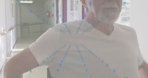 Senior man standing confidently in care corridor wearing v-neck shirt with perspective grid