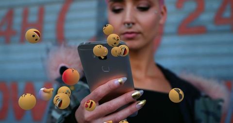 Woman interacting with floating emojis through smartphone