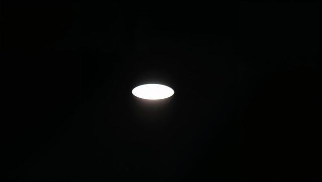 Round led ceiling light casting soft halo in dark minimal interior