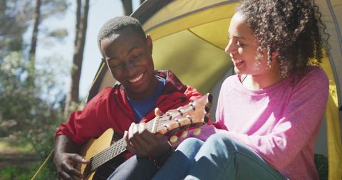 Cheerful Couple Enjoying Guitar Music in Scenic Tent Camping