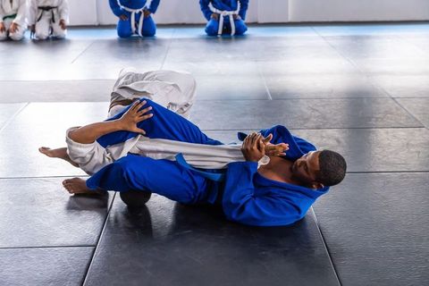Two grapplers practicing brazilian jiu-jitsu in a dojo