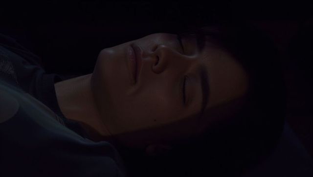 Adult woman lying and resting with closed eyes low-light intimate bedroom closeup portrait