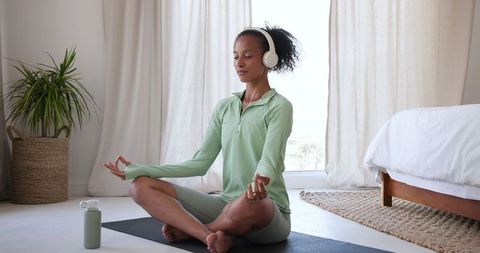 Mindful meditation practice by serene african american woman in bedroom