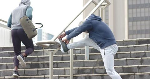 Mature african american men stretching and climbing urban stairs before outdoor workout