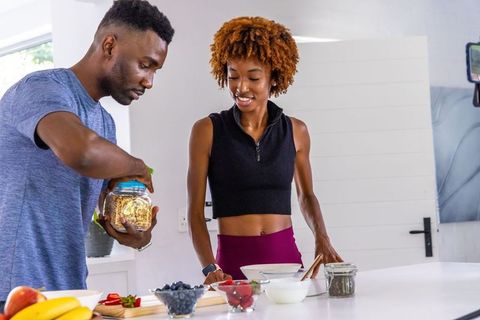 Couple preparing healthy granola and fruit breakfast in bright modern kitchen