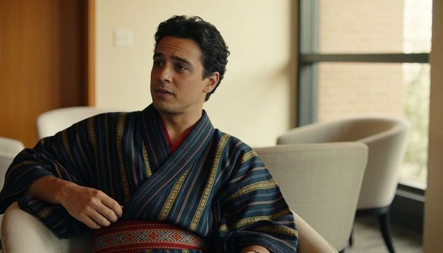 Contemplative man sitting in striped kimono robe leaning back in modern lounge with sash