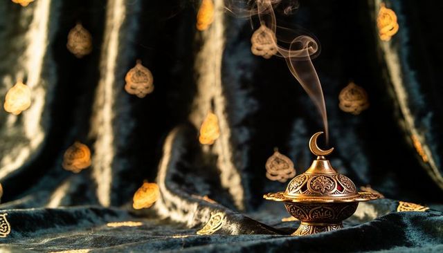 Ornate brass censer releasing curling smoke with crescent finial on velvet fabric