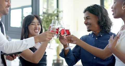 Group toasting with red wine in modern lounge celebrating networking success and friendship