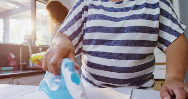 Person Ironing Clothes in Bright Kitchen - Download Free Stock Images Pikwizard.com